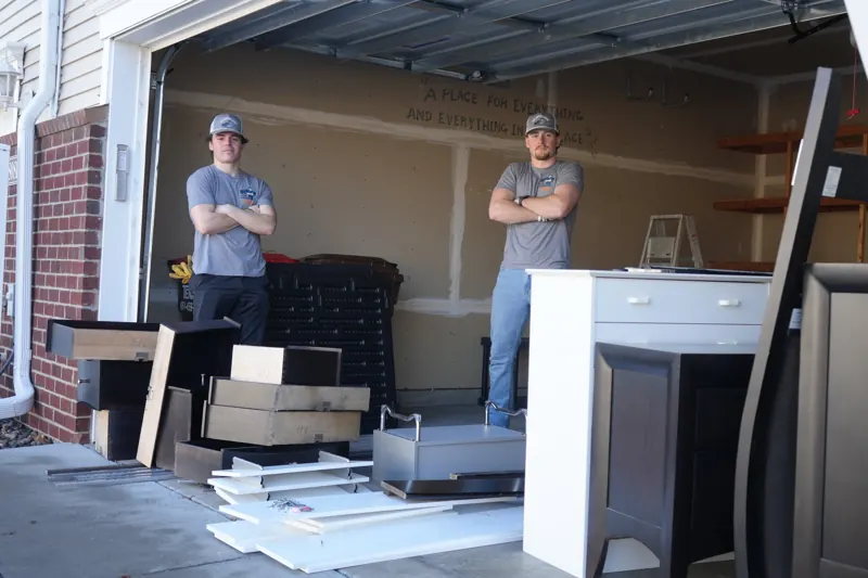 Two of the crew in a garage full of old cabinets and junk