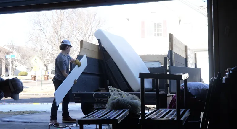Crew loading a mattress and furniture into the Joe Knows Junk trailer